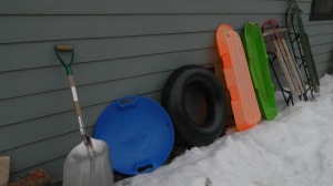 The line up...Starting from left to Right our snow shovel, disc, tibe, plastic sled tobaggon orange and green, the Topedo sled, and the green sled we call the General.